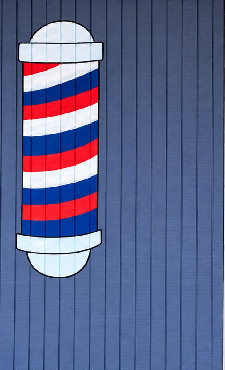 The hand-painted barber pole on the shop's blue front